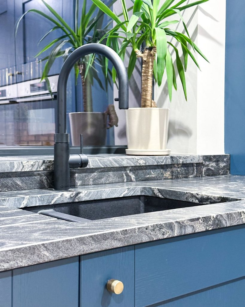 Bespoke kitchen detail with knurled bronze handle, veined stone worktop and deep blue cabinetry, from a Newcastle bespoke kitchen